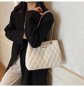 Détail du sac cabas matelassé blanc avec bandoulière dorée et logo métallique