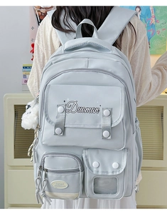 Detailed view of light blue-grey waterproof nylon backpack featuring a white plush charm