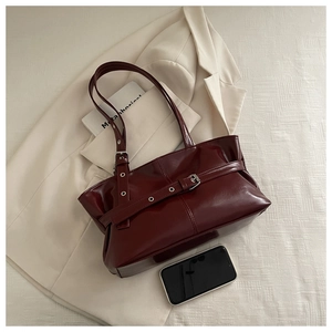 Detail of burgundy glossy oil-wax leather shoulder bag with silver metallic belt buckle