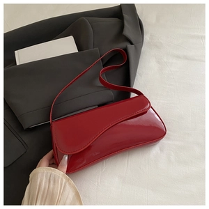 Detail of red patent leather shoulder bag with asymmetrical wave cut front flap and glossy finish