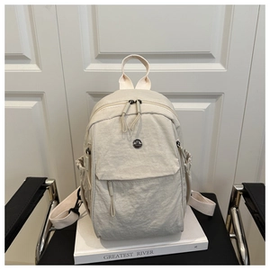 Detail of beige nylon backpack featuring side drawstring pockets on white book background