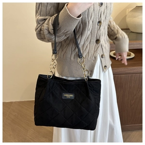 Detail showing the quilted diamond pattern and golden chain strap of the black tote bag