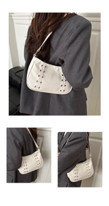 Detail view of white leather hobo bag featuring silver stud accents and shoulder strap