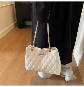 Détail d'un sac cabas blanc matelassé avec chaîne dorée et motif de losanges texturés