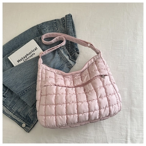 Macro view of a light pink quilted puffer bag showing zipper pocket and soft texture