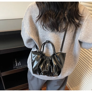 Detailaufnahme der schwarzen Plissee-Wolktasche mit glänzender Lederoptik und Schultergurt