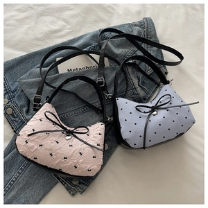 Détail de sacs à main demi-lune avec nœuds à pois et textures de broderie délicates