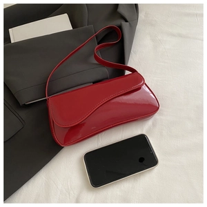Detail of red patent leather baguette bag with wavy flap and smartphone for scale