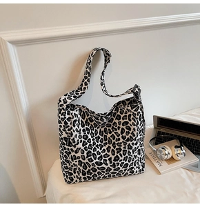 Detail of leopard print tote bag with adjustable strap and Fashion label on white surface