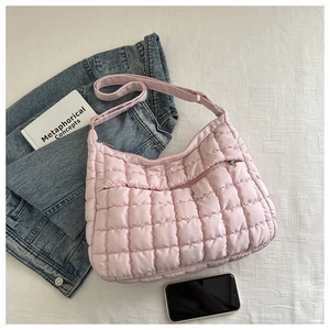 Close-up of pink quilted puffy shoulder bag with zipper pocket and adjustable strap