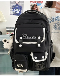 Detail of black nylon backpack with Duoman embroidery and cute white bear keychain accessory
