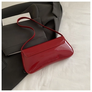 Close-up of vibrant red patent leather shoulder bag on a stylish grey suit jacket