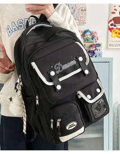 Detail view of black nylon backpack featuring contrast white piping and plush star charm