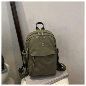 Detail view of army green nylon backpack showing front zip pocket and metal logo on the bag