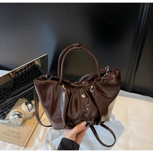 Nahaufnahme der dunkelbraunen Lackledertasche mit Falten-Design und glänzender Oberfläche
