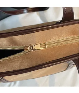 Gros plan du curseur de fermeture éclair en métal doré lisse sur un sac bicolore