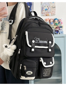 Detail of black and white nylon backpack with multi-pocket design and plush bear charm