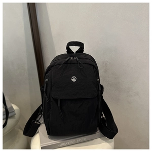 Detail of black oxford fabric backpack with M Fashion logo on a gray book