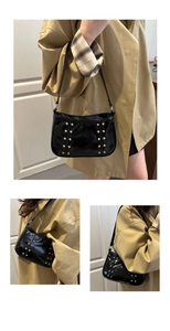 Detail of black patent leather crossbody bag with silver studs and polished finish