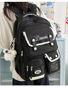 Detail of waterproof nylon backpack with white piping and plush bear accessory