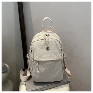 Detail view of water-resistant off-white nylon backpack with drawstrings and logo