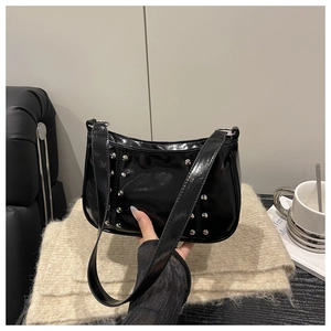 Detail of glossy black patent leather shoulder bag with silver rivet studs