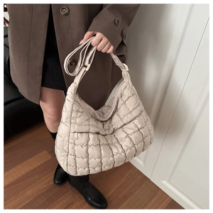 Detailed close-up of quilted beige puffer tote bag texture with soft padded stitching