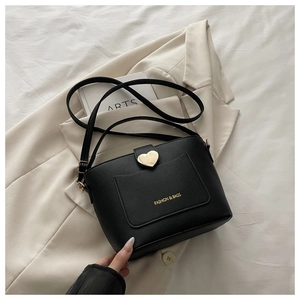 Détail du sac seau noir en cuir grainé avec un fermoir doré en forme de cœur élégant