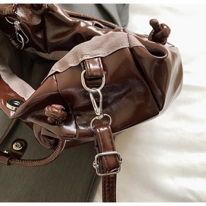 Detail der dunkelbraunen glänzenden Handtasche mit Silberschnalle und Magnetverschluss