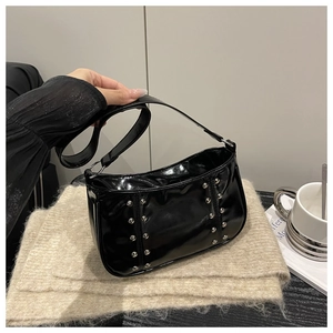 Detail of black patent leather underarm bag with silver rivets and metal ring connectors