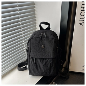 Close-up of black nylon backpack with ruched texture and round metallic M badge