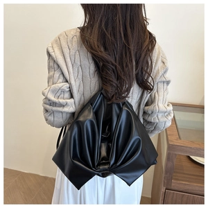 Dettaglio del grande fiocco e della pelle PU della borsa a tracolla nera alla moda