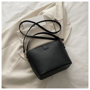 Vue de dessus d'un sac seau noir en cuir grainé avec détails dorés sur un fond de costume