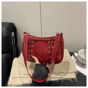 Detail of red patent leather shoulder bag with vintage silver rivets and smooth glossy finish