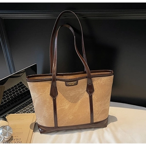 Sac fourre-tout beige avec bordure en cuir marron sur un bureau avec ordinateur