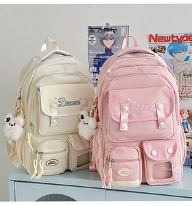 Detail of multi-pocket nylon backpacks in beige and pink with cute plush bear charms