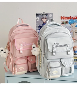 Pink and grey preppy school backpacks with plush bear pendants on display