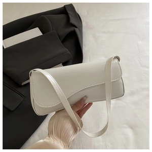 Detail of white glossy patent leather rectangular shoulder bag with slim strap held in hand