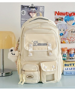 Detail of a beige multi-pocket nylon backpack with a plush star charm and logo print