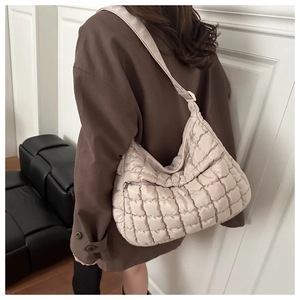 Detail of beige quilted puffer shoulder bag showing square padded texture and wide strap