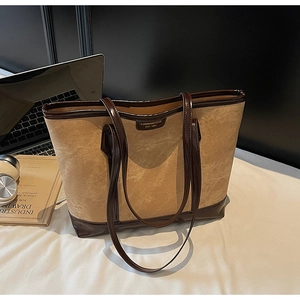 Détail d'un grand sac cabas en daim kaki avec garniture en cuir marron et ordinateur portable