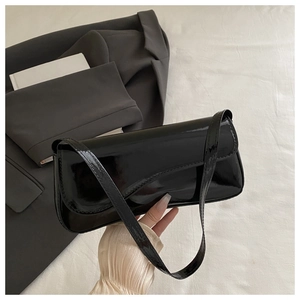 Glossy black patent leather bag shown on grey blazer with a minimalist sleek finish