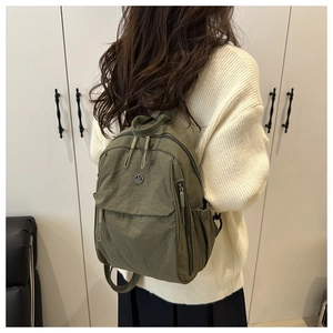 Detail view of olive green waterproof nylon mini backpack with metal M logo on back