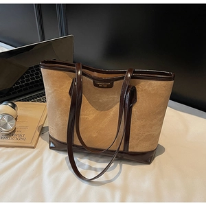 Détail du sac cabas en daim beige avec bordure en cuir verni brun et logo doré