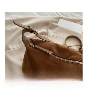 Detail view of brown suede tote bag featuring metallic zipper and adjustable shoulder strap