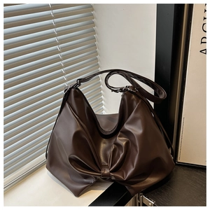Detailed close-up of dark brown soft leather tote bag showing unique bow-shaped fold design
