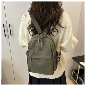 Close-up of olive green nylon crossbody bag with metal M logo and zipper details