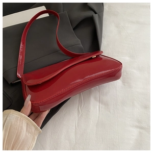 Detailed top view of red patent leather baguette bag with shiny texture and golden buckle