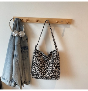 Leopard print canvas tote bag hanging with denim jacket and silver headphones
