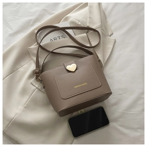 Détail du sac seau beige foncé avec texture cuir lychee et fermoir coeur en métal